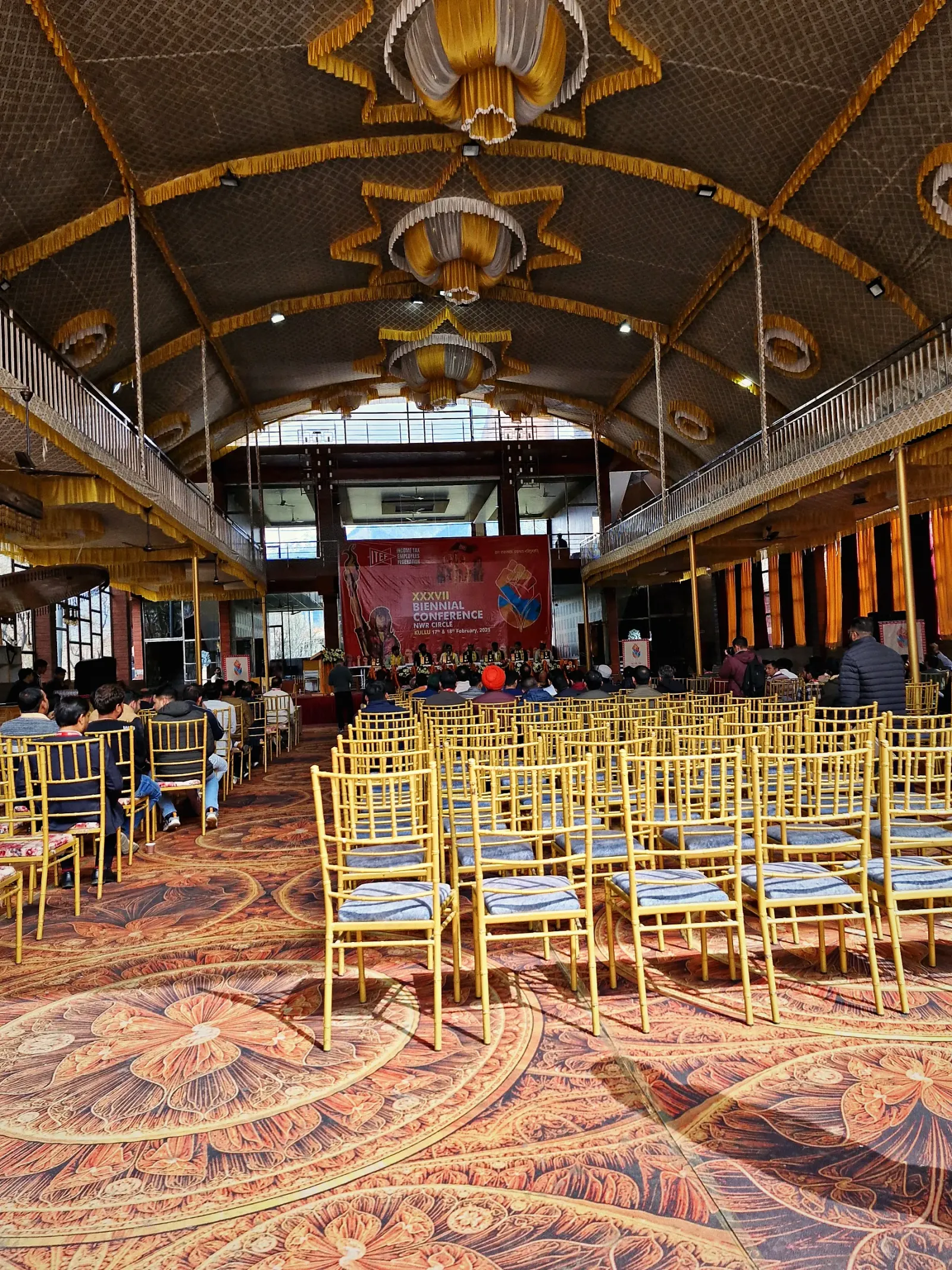 Rows of chairs set for a ceremony under a decorated gold canopy