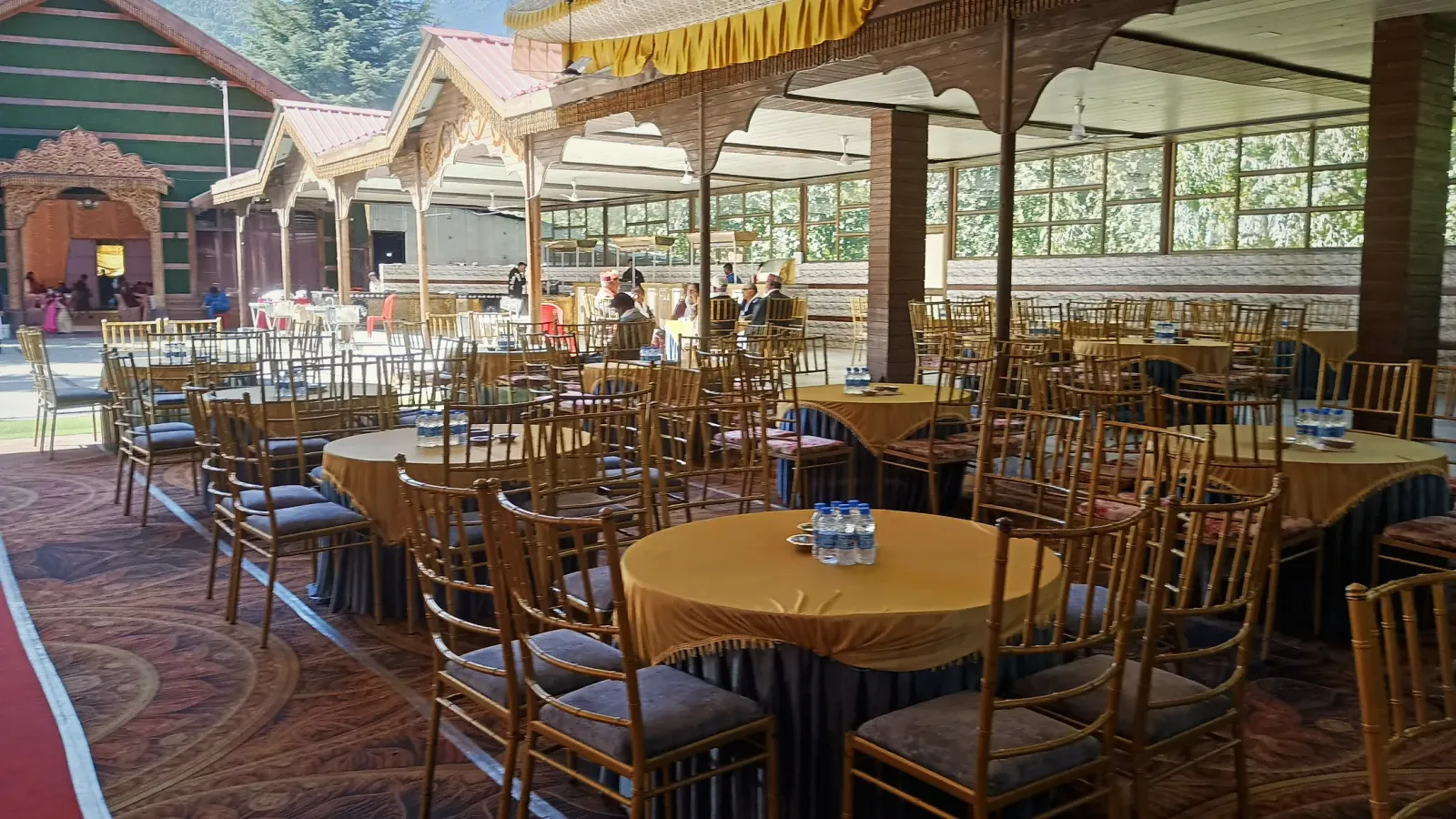 Round tables with gold chairs laid out in the glass-walled banquet hall