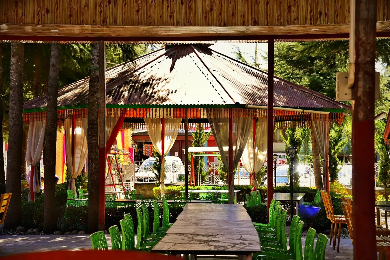 A wooden gazebo in the garden with a long table beneath it