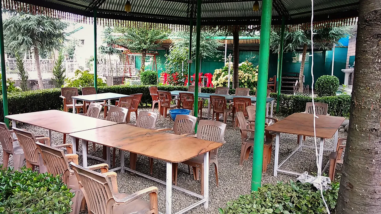 Garden cafe tables under a green canopy among the trees