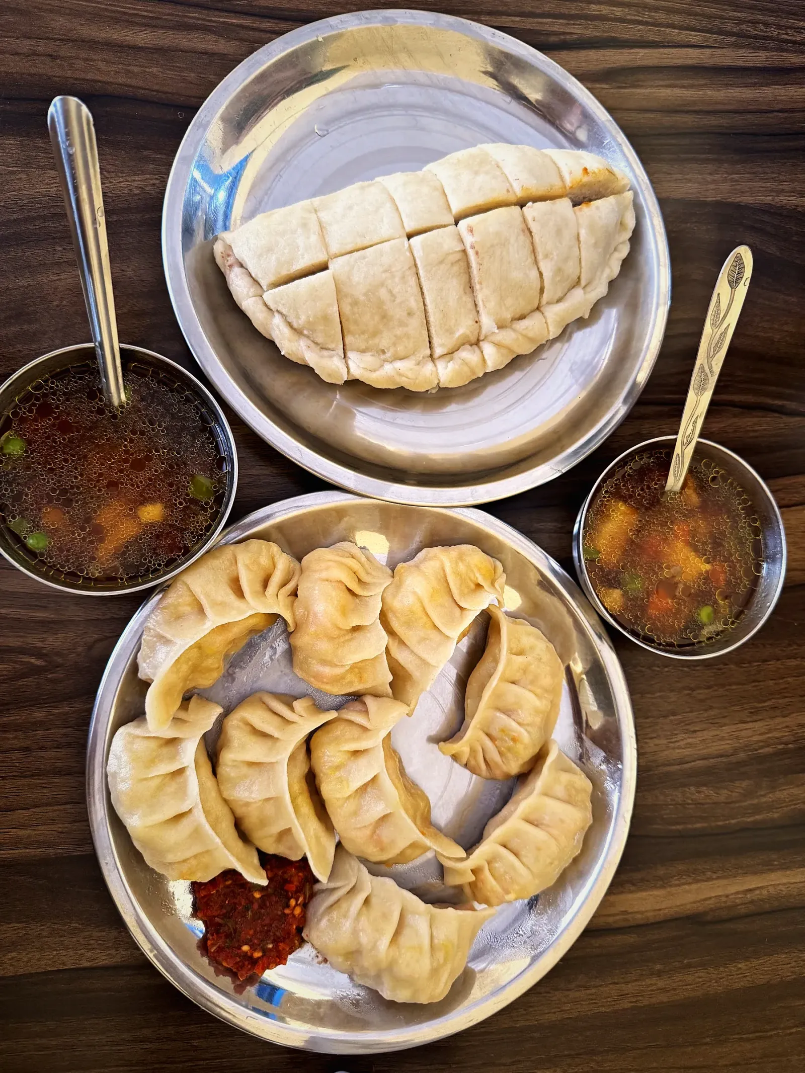 Plates of steamed momos with soup and chutney