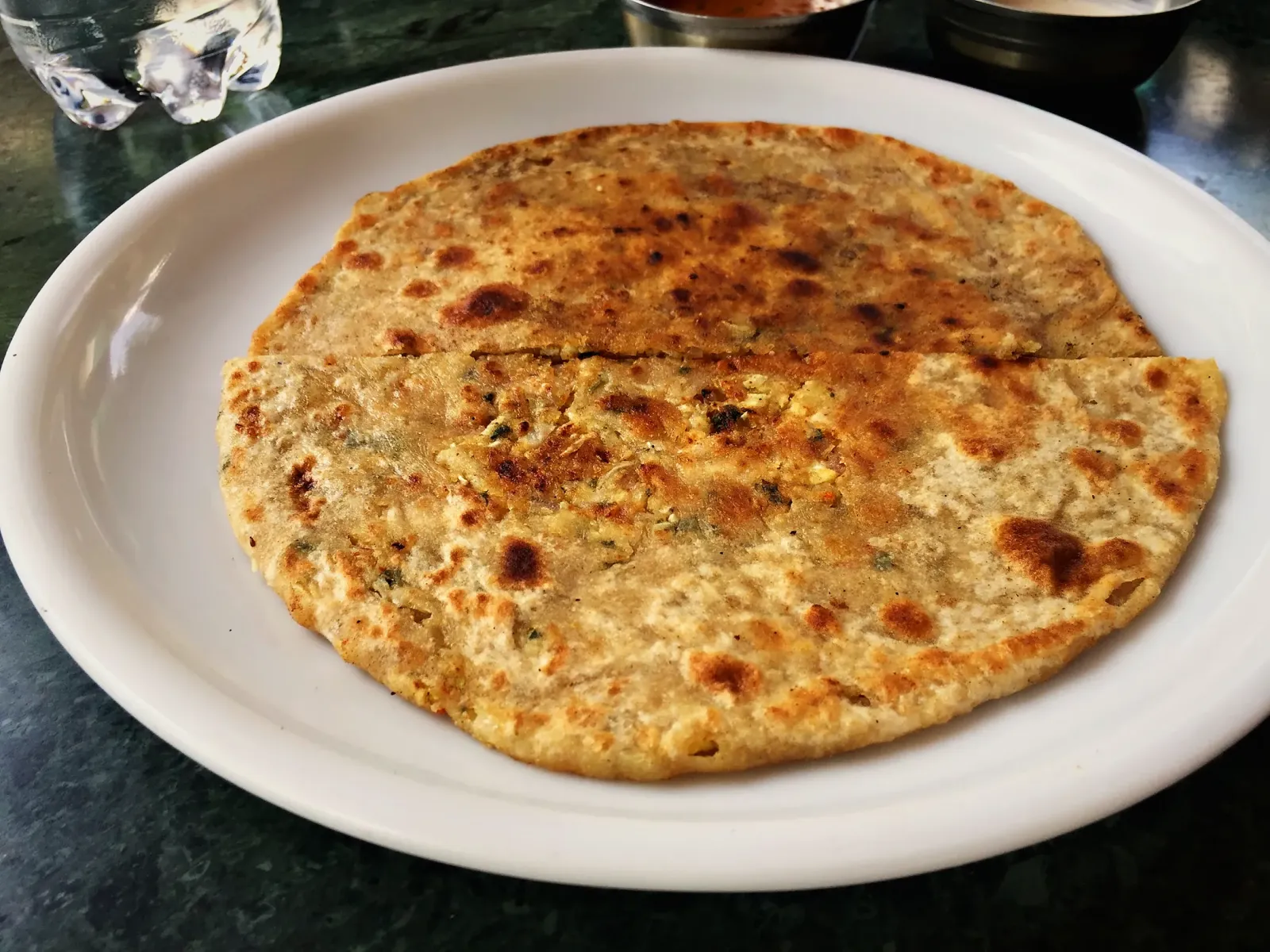 A golden stuffed paratha on a white plate