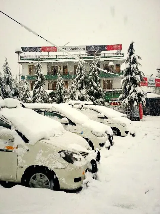 Cars under deep snow in front of the hotel in winter