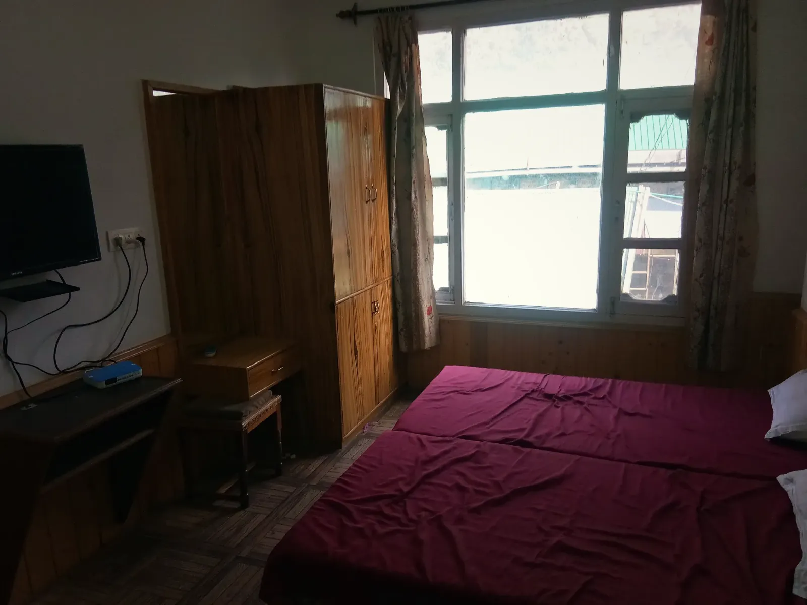 A guest room with a large window, desk and television