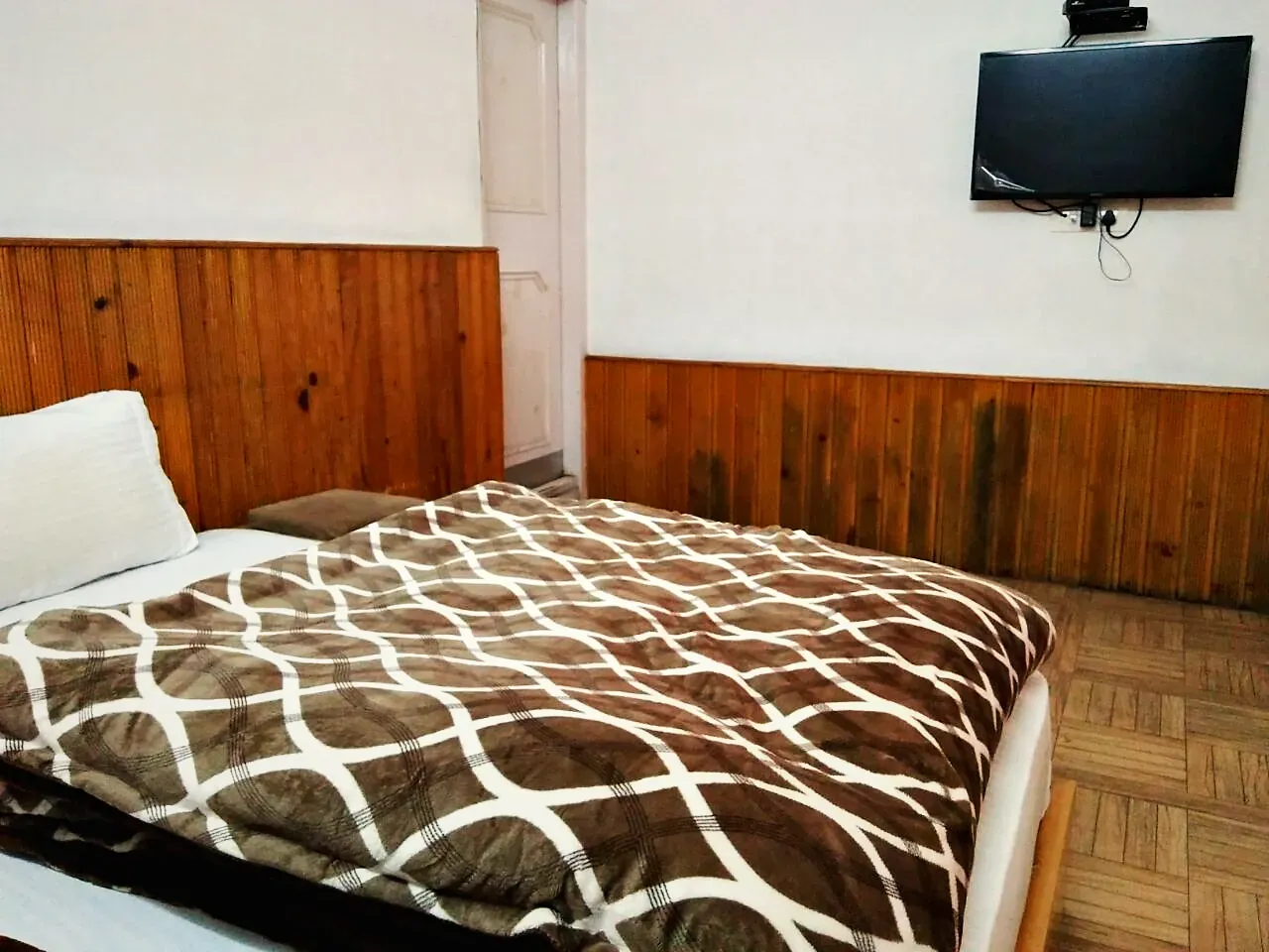 A double bed with a patterned blanket in a wood-panelled room
