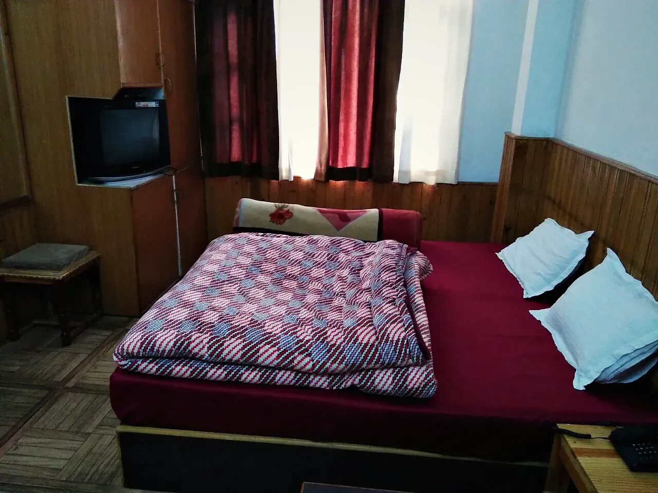 A guest room with a checked quilt and pine panelling